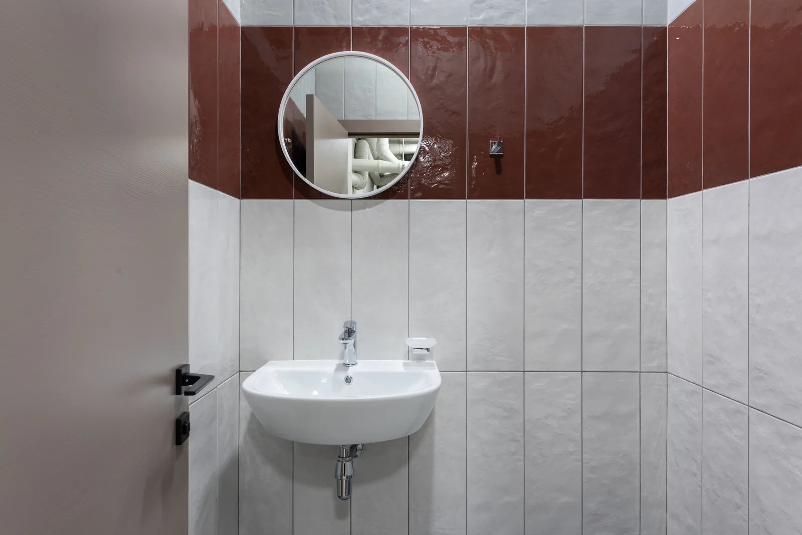 Clean commercial restroom sink with tile wall